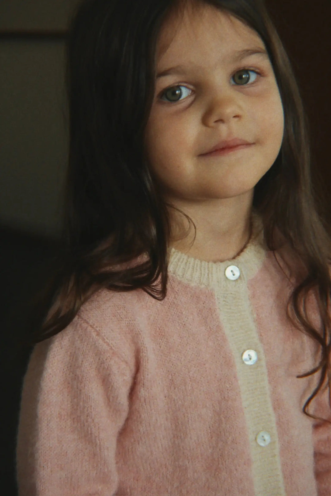 Konges Slojd Kitty Cardigan silver pink getragen von einem Mädchen mit Fokus auf die obere Hälfte des Cardigans mit Blick auf die Knopfleiste aus Perlmutt.