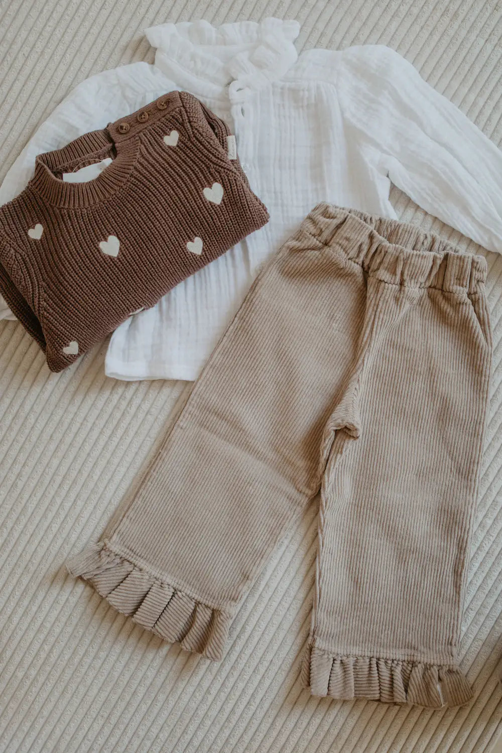 Leevje Cordhose mit Rüschen dusty rose drapiert mit dem Strickpullover Hearts in pecan und der Musselin Bluse Mini Me in white. 