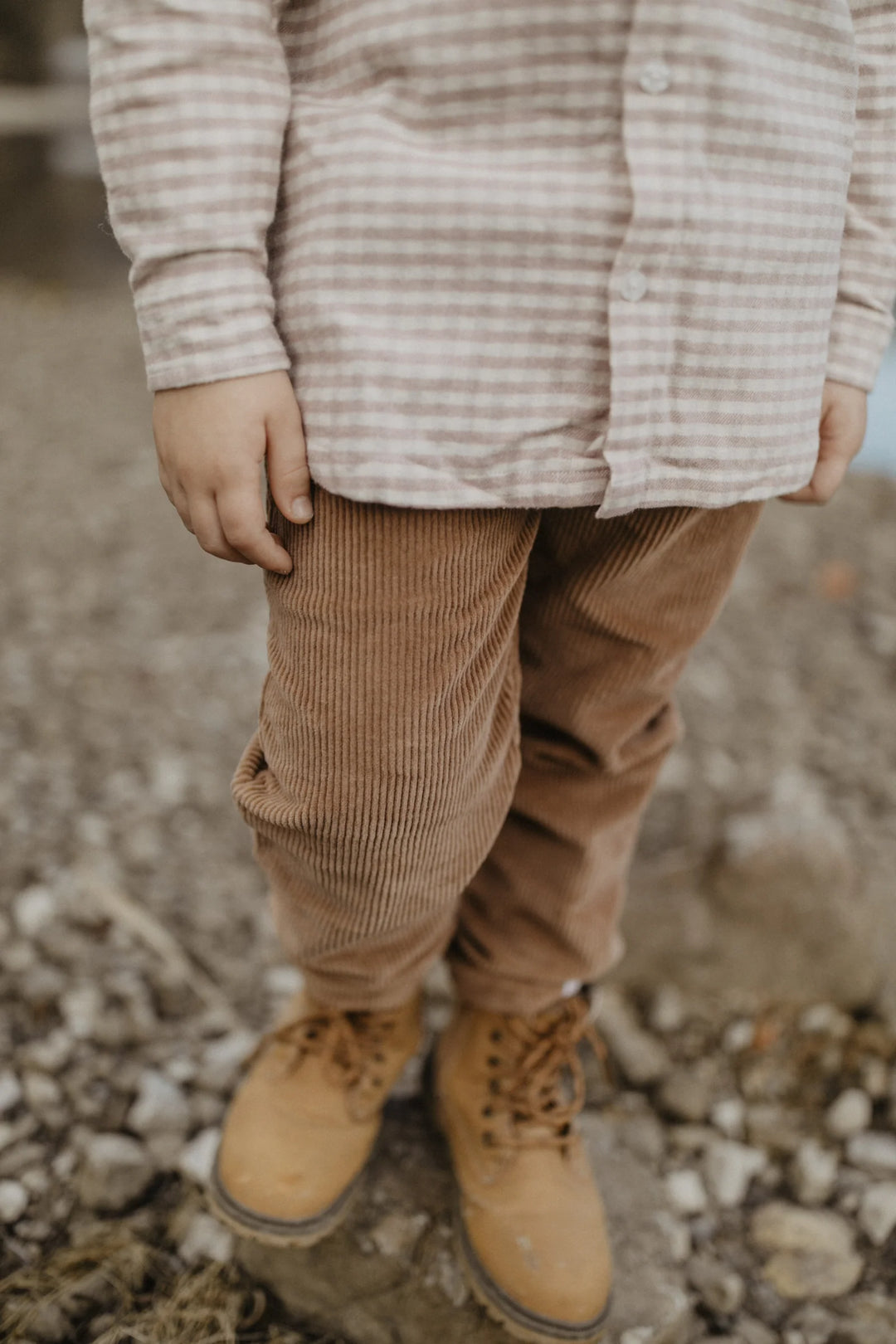 Leevje Corduroy Pants pecan getragen von einem Kind, Detailansicht Cordstoff, Ansicht von vorne. 