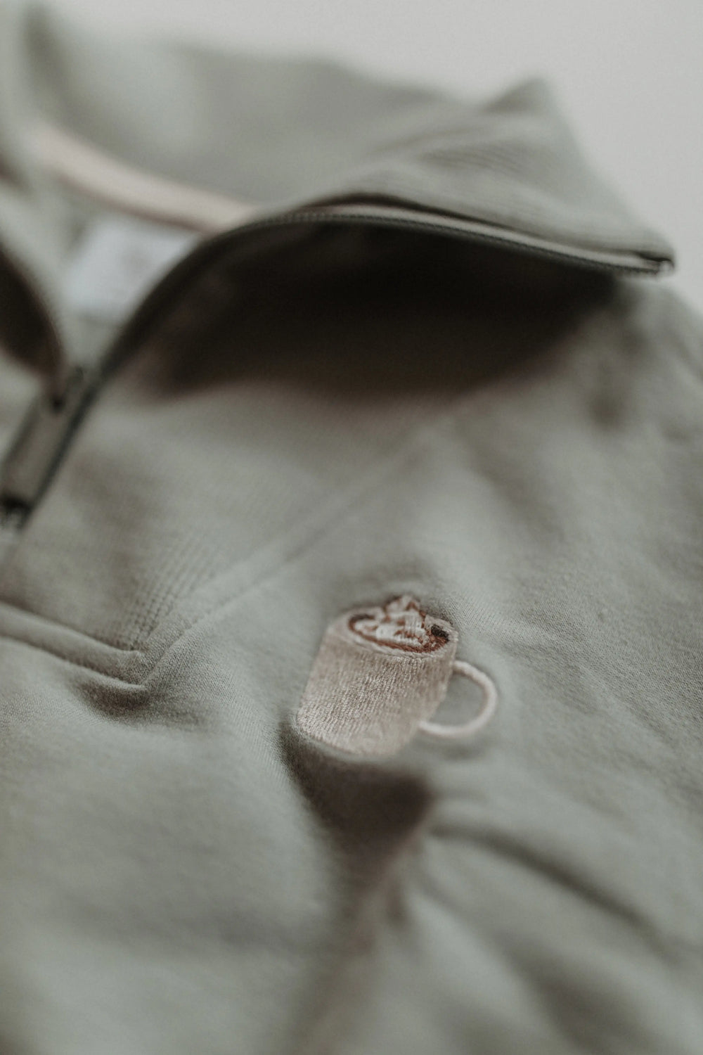 Leevje Troyer Half-Zip Sweater Cocoa green Detailansicht aufgestickte Tasse mit Kakao und Sahnehaube.