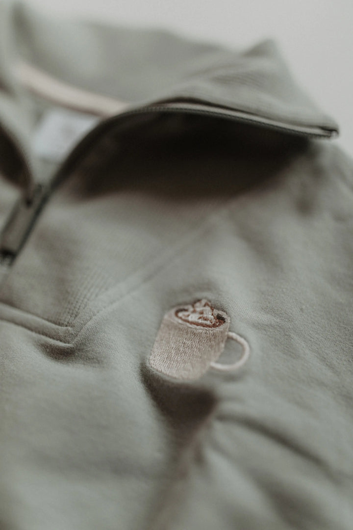 Leevje Troyer Half-Zip Sweater Cocoa green Detailansicht aufgestickte Tasse mit Kakao und Sahnehaube.