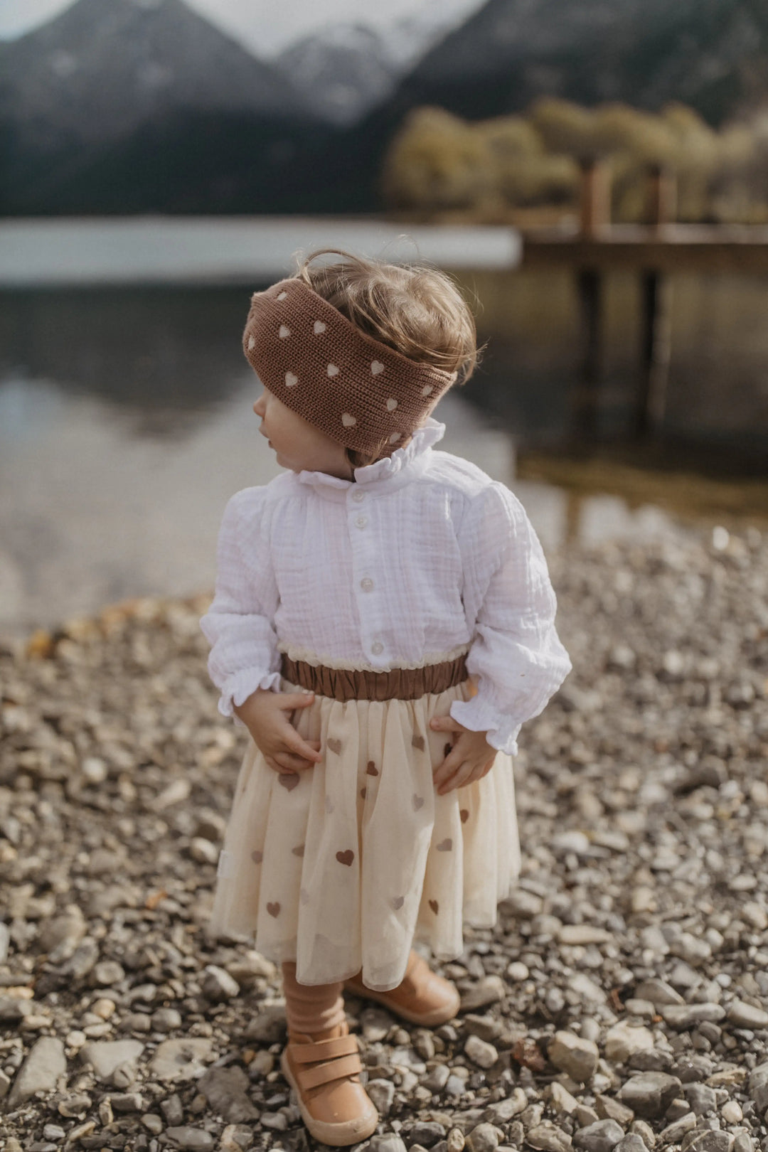 Leevje Tulle Skirt hearts light beige getragen von einem kleinen Mädchen am Ufer eines Sees stehend, Ansicht von vorne. Kombiniert mit der Muslin Blouse. 