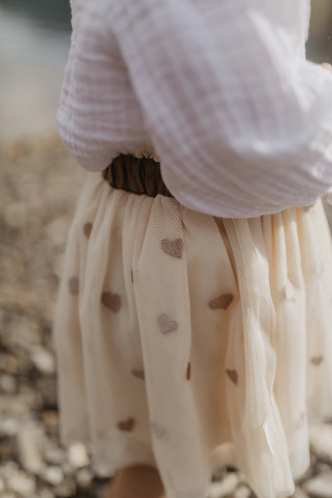 Leevje Tulle Skirt hearts light beige getragen von einem kleinen Mädchen, Detailansicht Tüll mit aufgestickten Herzen. 