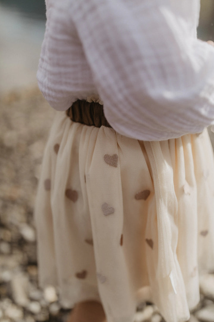 Leevje Tulle Skirt hearts light beige getragen von einem kleinen Mädchen, Detailansicht Tüll mit aufgestickten Herzen. 