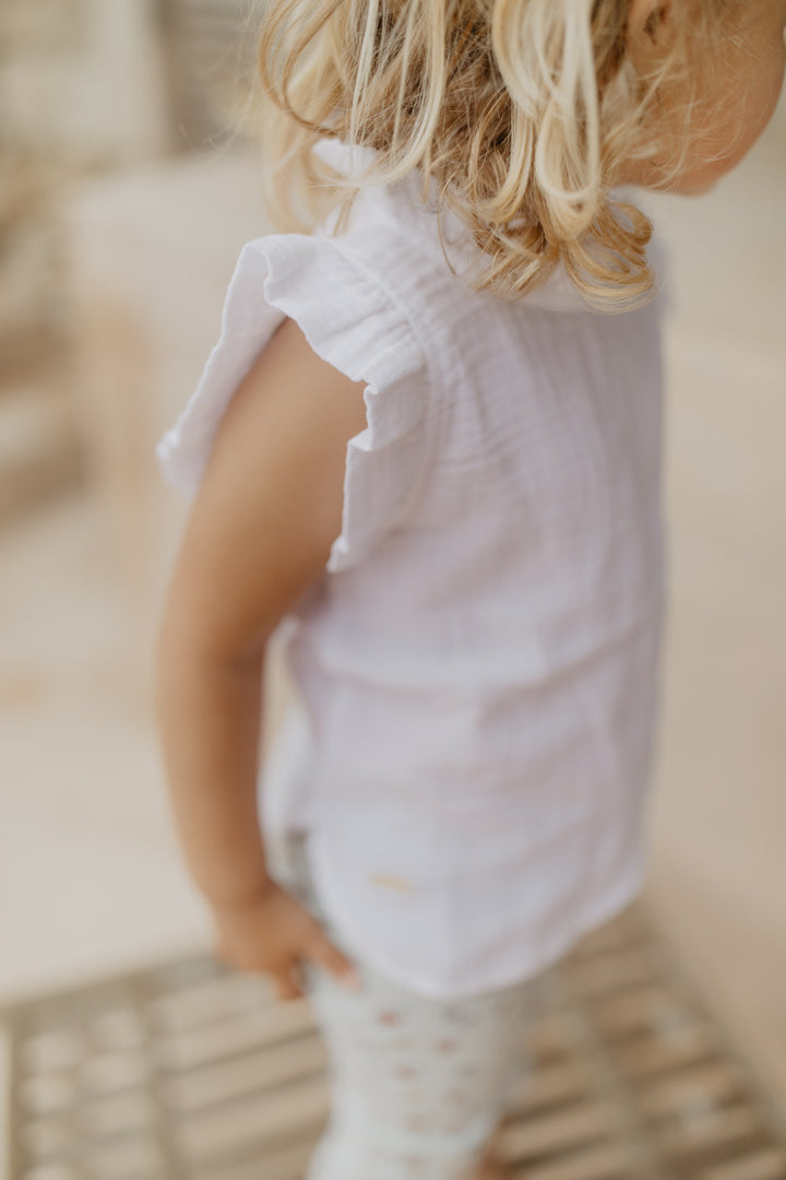 Leevje muslin top with ruffles white getragen von einem Mädchen, Fokus auf Rüschen am Armabschluss