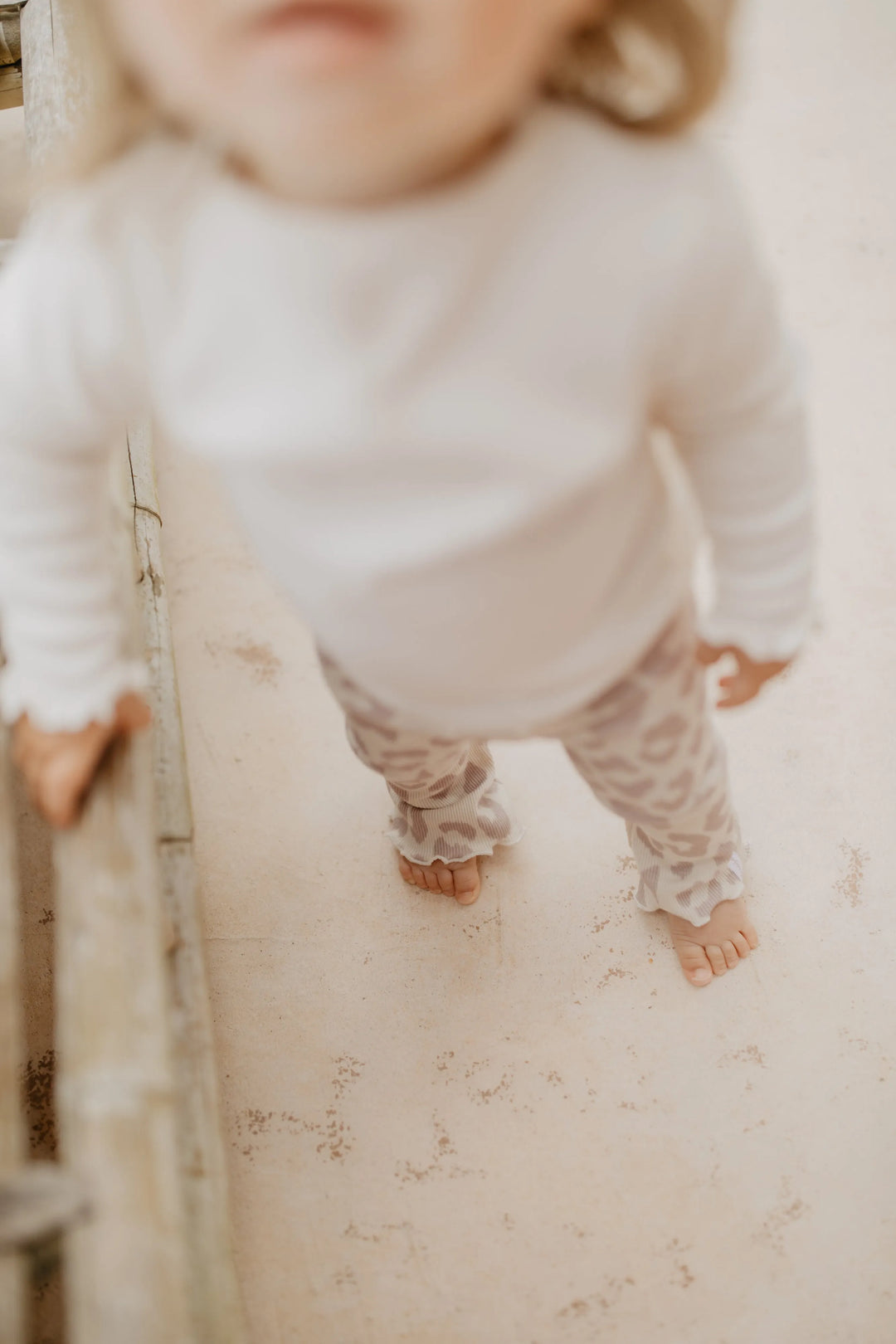 Leevje rib knit flared leggings leo getragen von einem Baby-Mädchen, Blick von oben mit Fokus auf den gerüschten Saum am Fuß