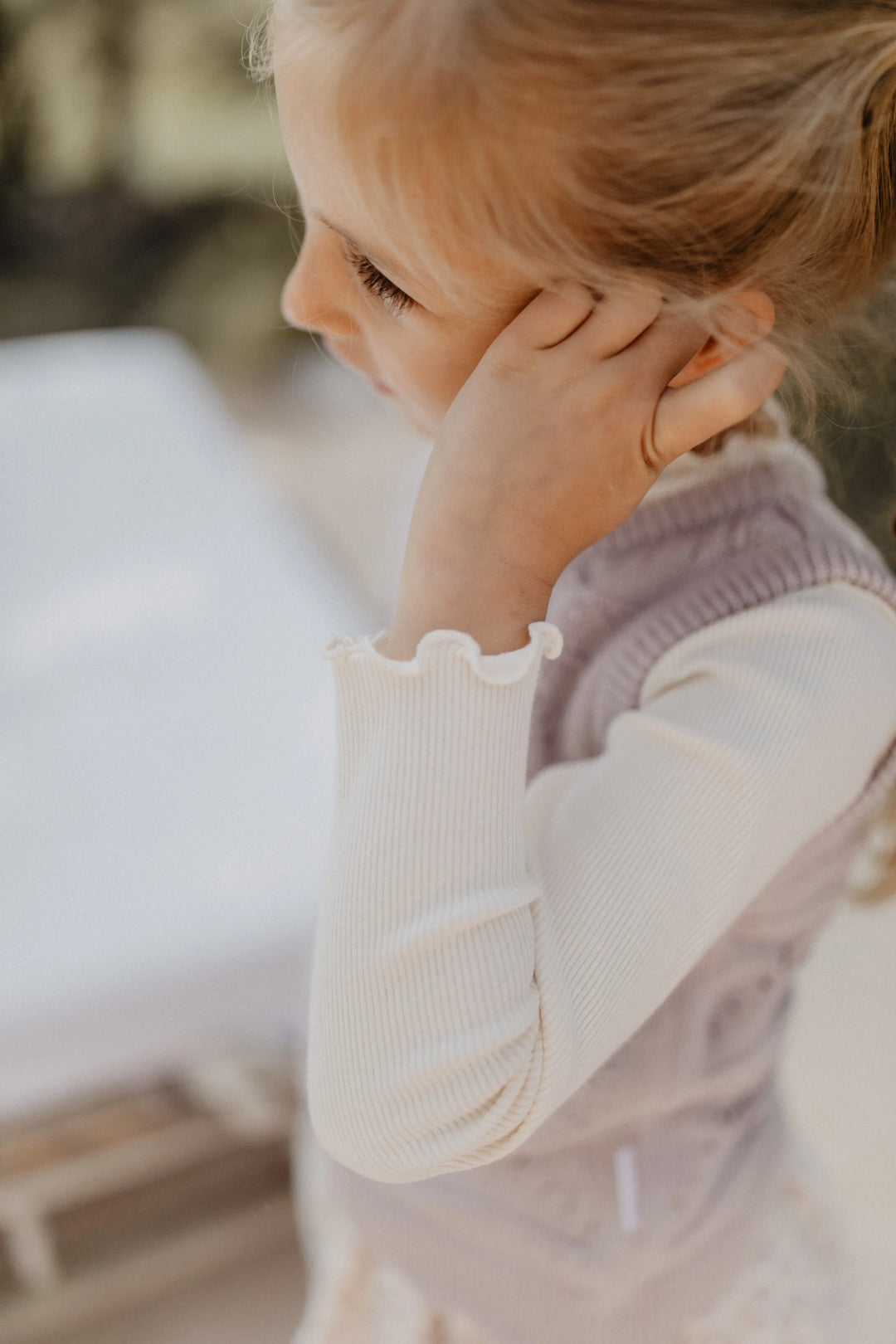 Leevje rib knit long sleeve light beige getragen von einem Mädchen, Fokus auf rechten Ärmel mit gerüschtem Saum