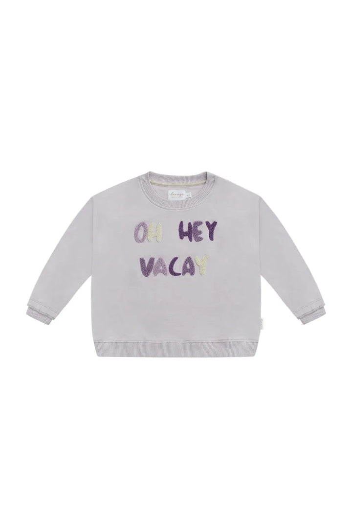 hell-lilafarbenes Sweatshirt für Mädchen aus 100% Bio-Baumwolle mit Frottee Schriftzug "oh hey vacay" in verschiedenen Lila-Tönen und weiß, gerippte Bündchen und Rüschen am Armabschluss