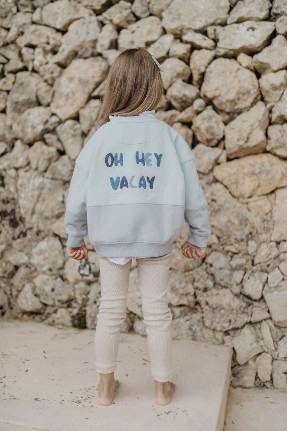 Leevje unisex oversized sweatshirt with shark oh hey vacay aqua getragen von einem Mädchen, Ansicht der Rückseite mit Blick auf den Schriftzug 