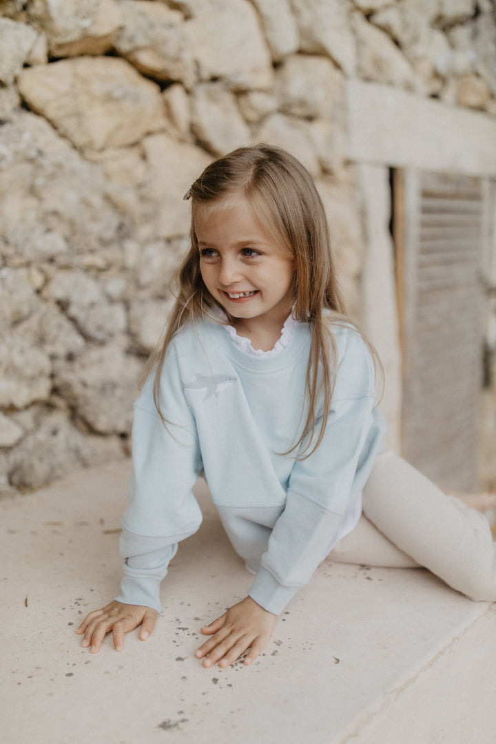 Leevje unisex oversized sweatshirt with shark oh hey vacay aqua getragen von einem Mädchen, Ansicht von vorne mit Blick auf aufgestickten Hai