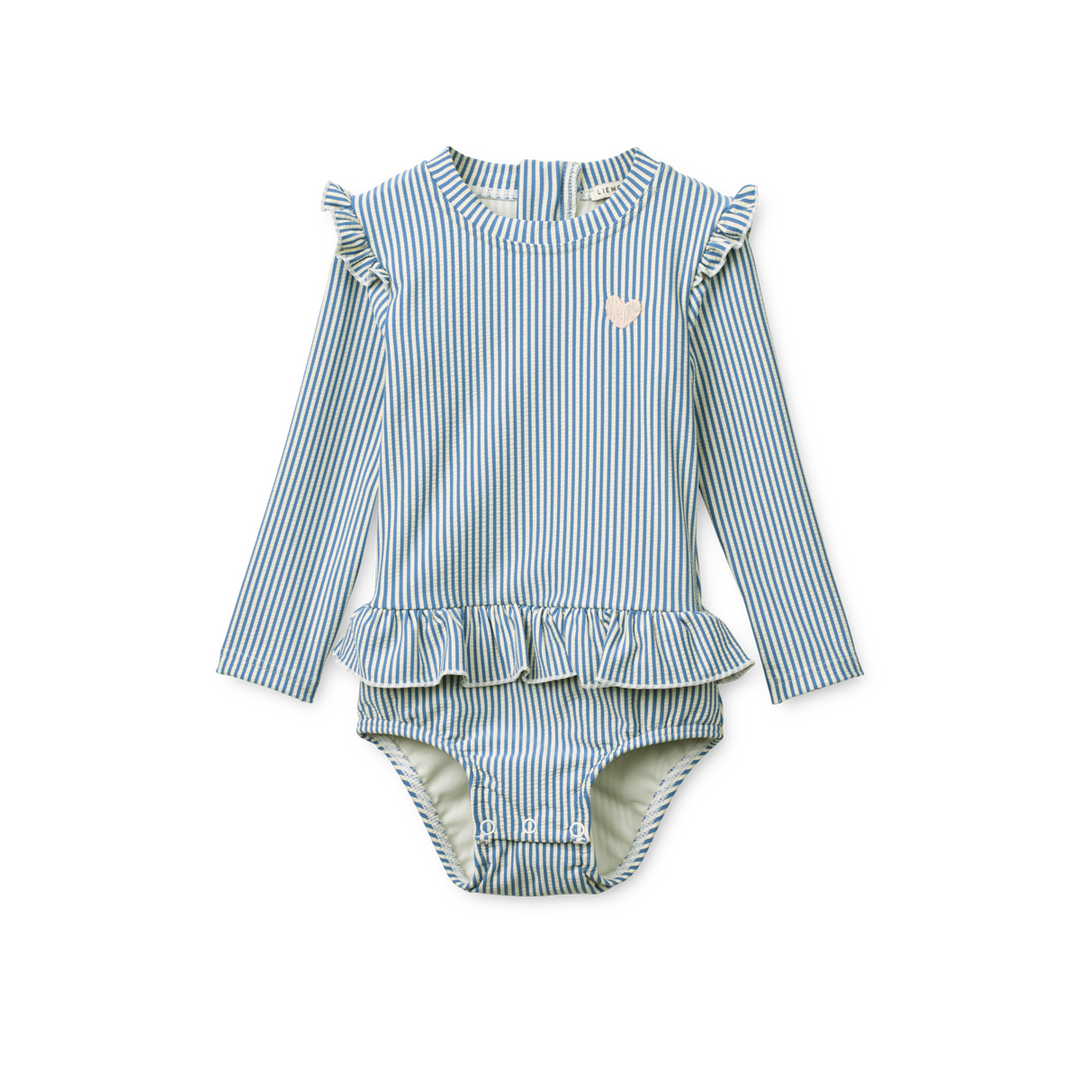 langärmeliger Badeanzug für Baby-Mädchen mit weiß-blauen vertikalen Streifen, Rundhalsausschnitt, Rüscxhen an den Schultern und einem angedeuteten Rüschen-Röckchen auf Höhe der Hüfte, Reißverschluss auf dem Rücken und Druckknöpfe im Windelbereich