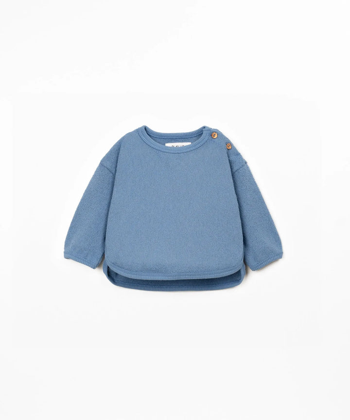 hellblauer Jersey Sweater für Babys und Kleinkinder mit lässigem boxy Schnitt, überschnittenen Schultern, Rundhalsausschnitt und Knöpfen auf der linken Schulter für ein leichtes An- und Ausziehen.