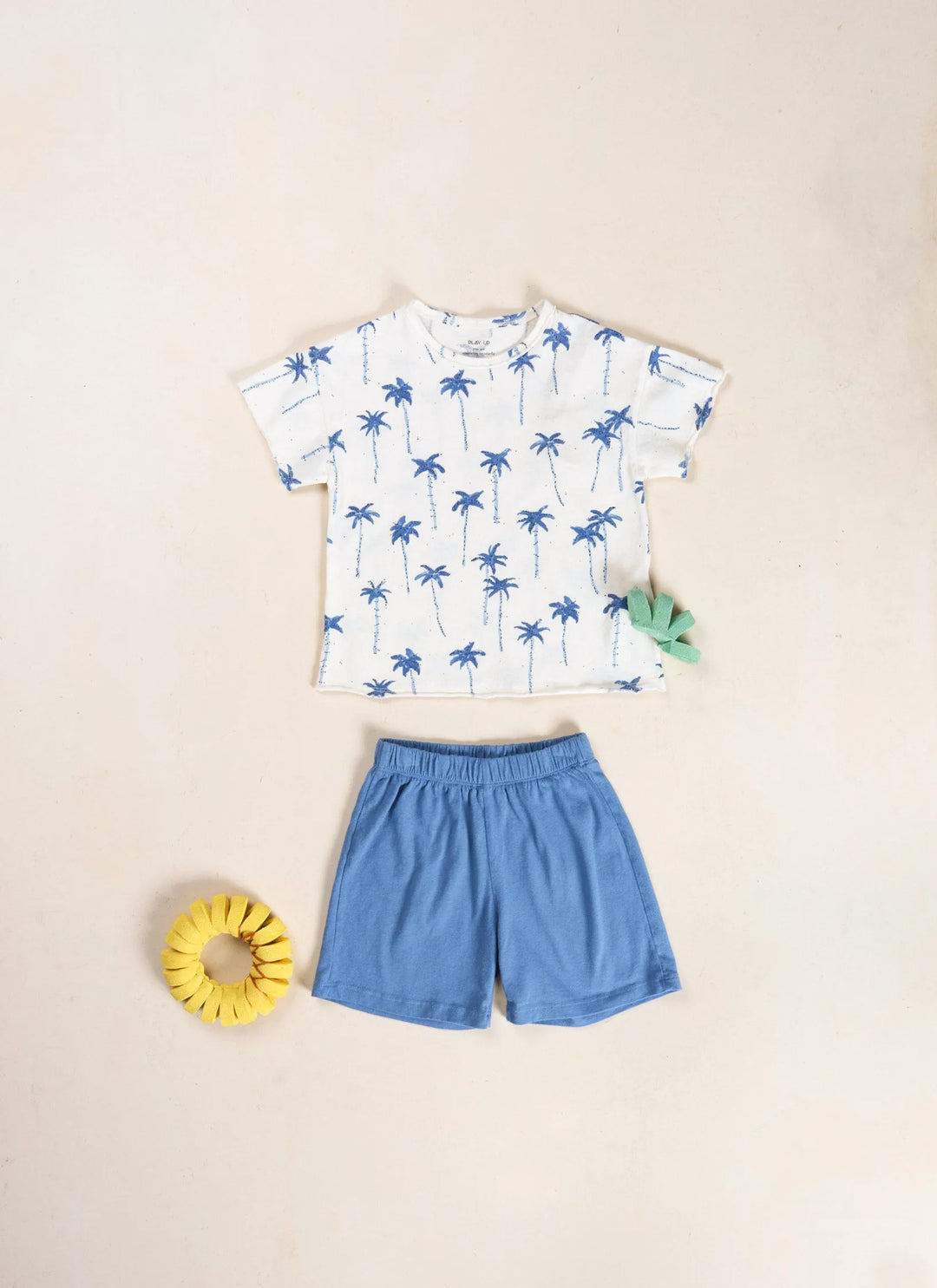 Play Up Printed Jersey T-Shirt bio resin auf beigefarbenem Hintergrund liegend und kombiniert mit einer mittelblauen Shorts