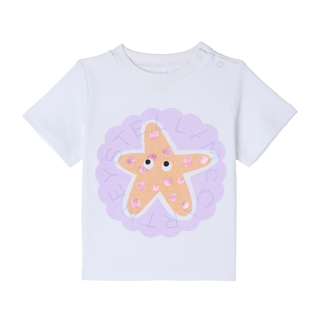 weißes T-Shirt für Baby-Mädchen aus 100% Baumwolle mit großem, aufgedrucktem gelbem Seestern mit Augen und rosafarbenen Glitzerpunkten auf hell-lilafarbenem, kreisrundem Hintergrund und Stella-Schriftzug auf der Vorderseite