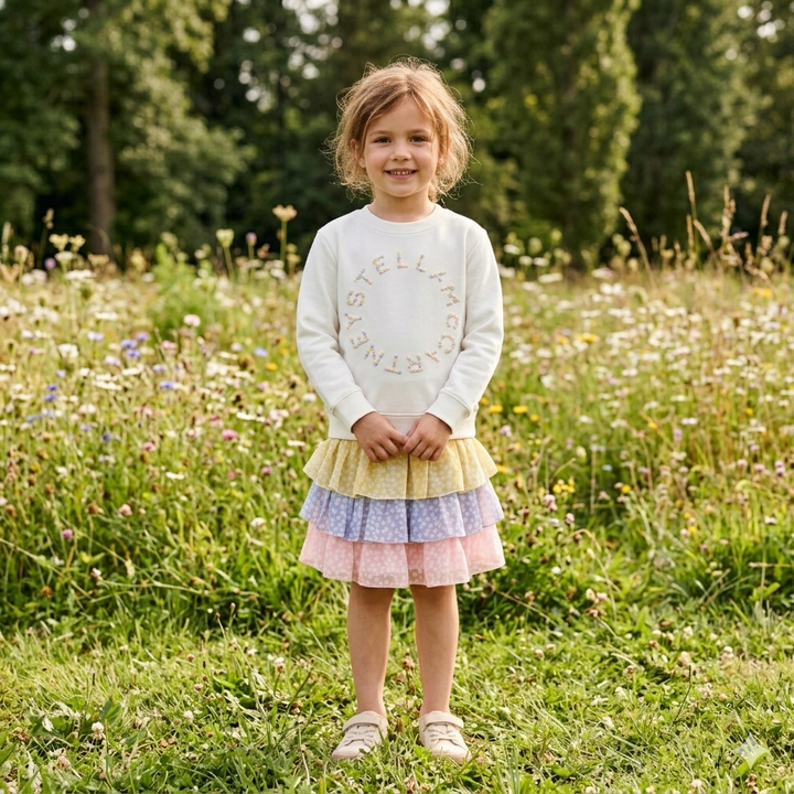 Stella_McCartney_TY4C10_Cotton_Fleece_Sweatshirt_ivory getragen von einem Mädchen vor einer Blumenwiese stehend, Ansicht von vorne
