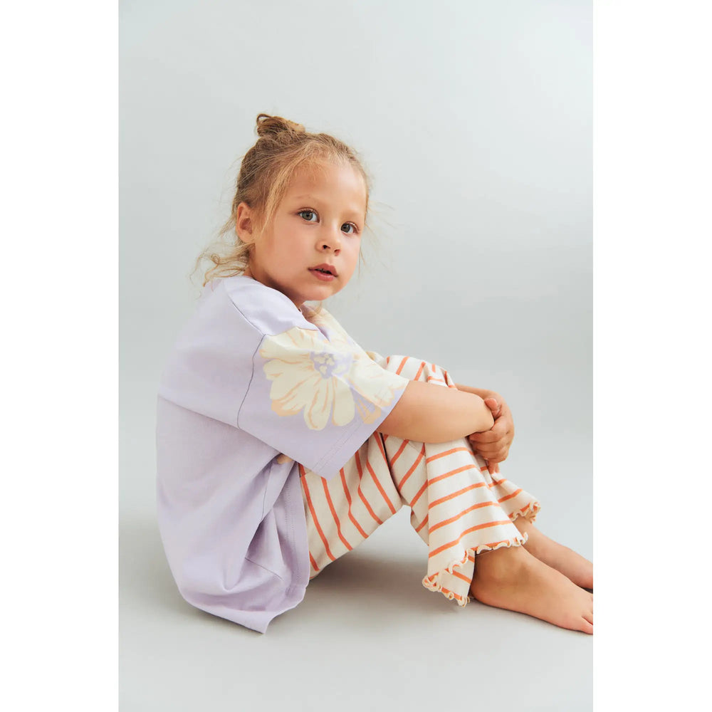 Wheat Jersey Pants Ela orange stripe  getragen von einem Mädchen, sitzend vor weißem Hintergrund, Ansicht von der Seite 