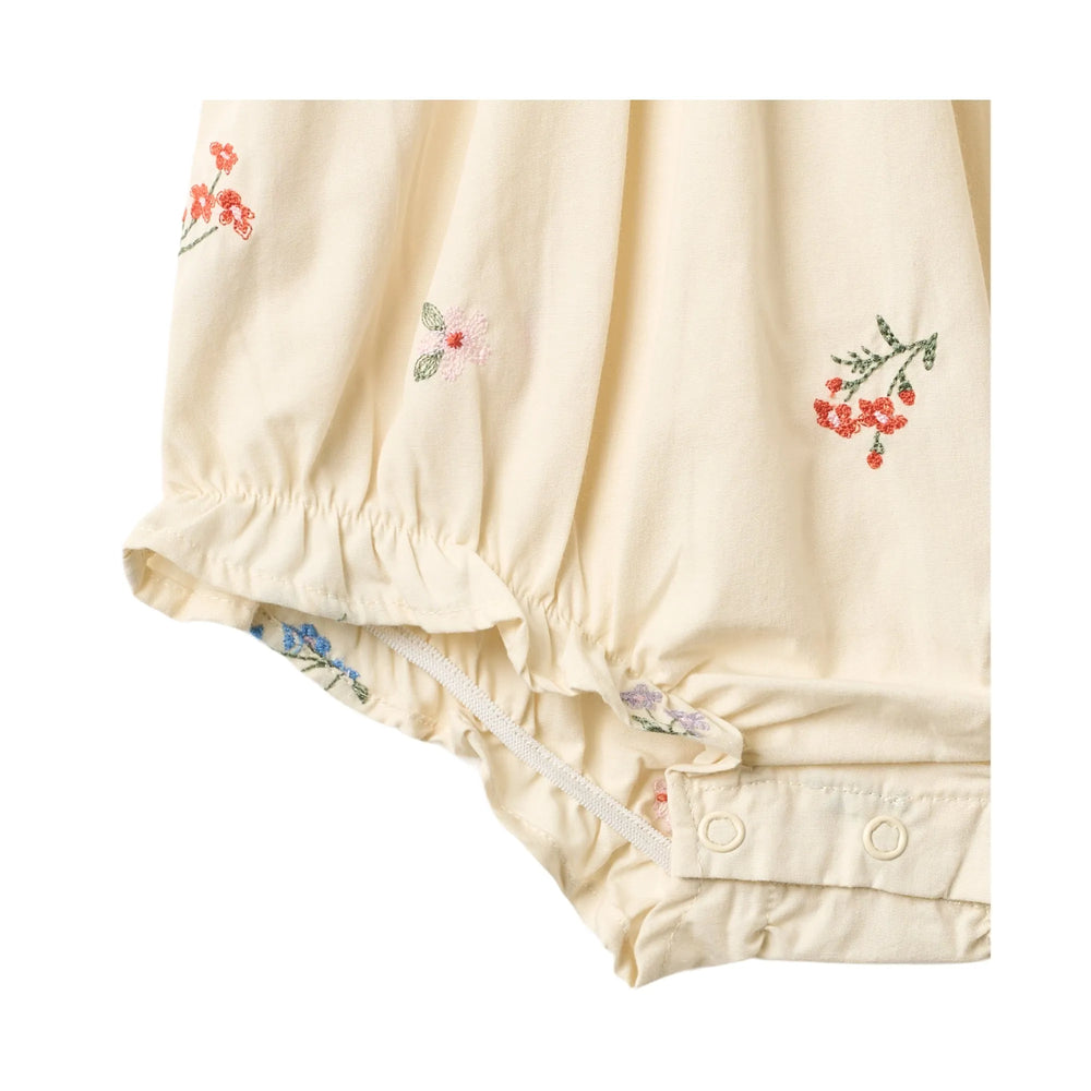 Wheat Romper Margit ivory embroidery flowers Detailansicht aufgesticktes Blumenmuster, Druckknöpfe im Windelbereich und Raffungen an der Beinöffnung