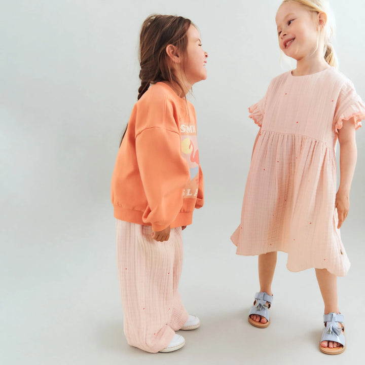 Wheat Sweatshirt Eliza sunkissed orange getragen von einem Mädchen vor weißem Hintergrund, Ansicht von der Seite