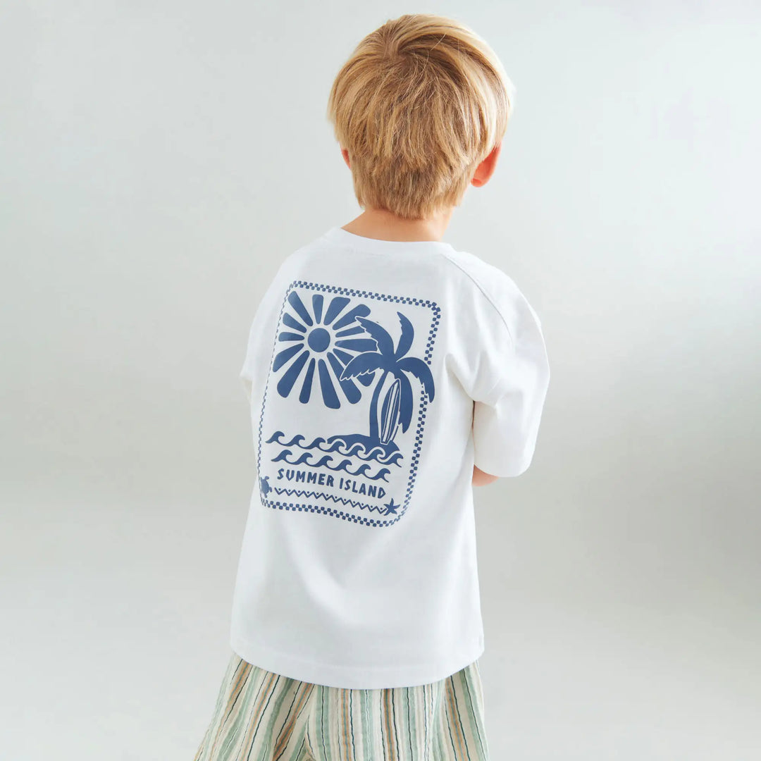 weißes kurzarm T-Shirt für Jungen aus Bio-Baumwolle mit ERundhalsausschnitt, Surfbrett-Print auf der linken Brust und Surfbrett, Palmen, Sonnen-Print auf dem Rücken in blau, getragen von einem Jungen, Ansicht der Rückseite mit großem Print