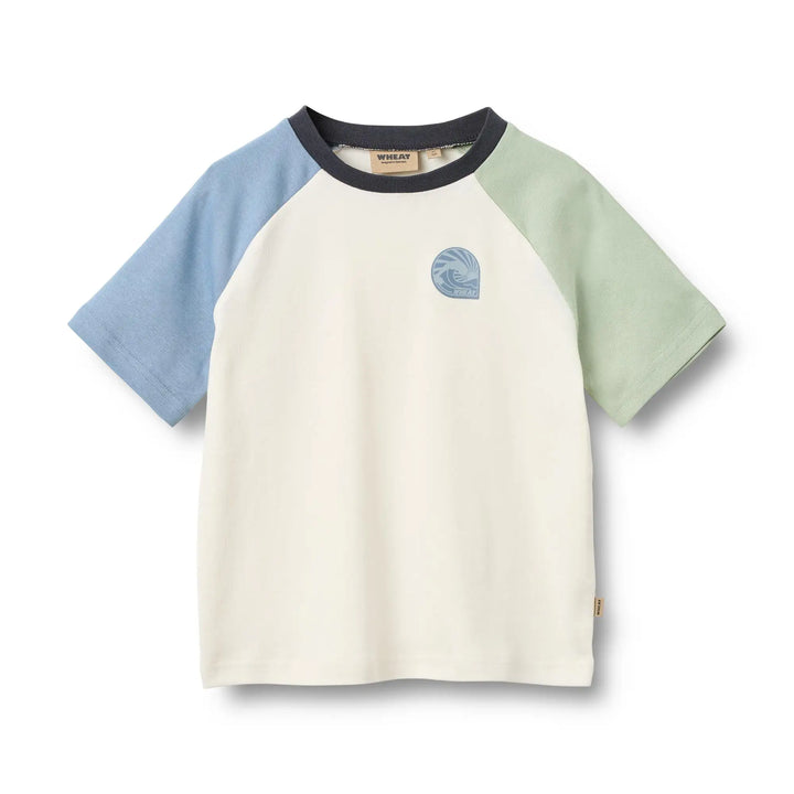 elfenbeinfarbenes, kurzärmeliges T-Shirt für Jungen aus Bio-Baumwolle mit Raglanärmeln, einer hellblau, einer hellgrün, dunkelblauem Rundhalsausschnitt und kleinem Wellenprint auf Höhe der linken Brust