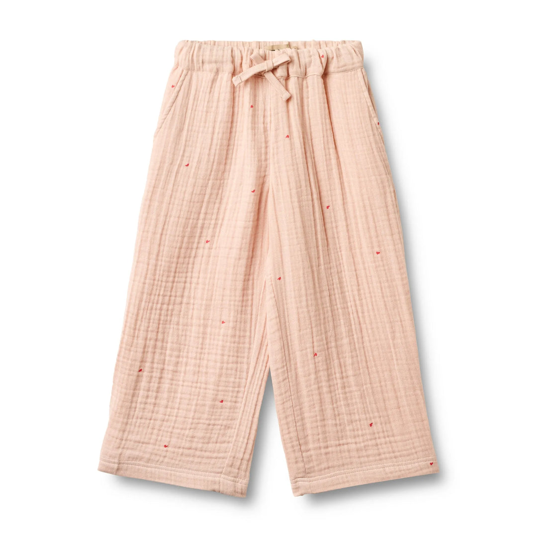 pfirsich-rosafarbene Hose für Mädchen aus Musselin aus Bio-Baumwolle mit weitem Bein, Gummibund, seitlichen Eingriffstaschen und aufgedruckten kleinen roten Herzen mit größerem Abstand zueinander