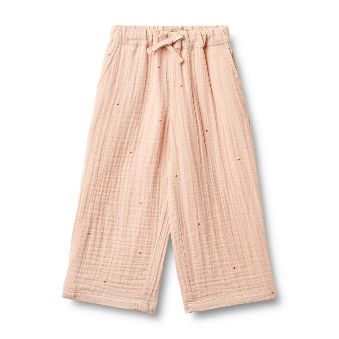 pfirsich-rosafarbene Hose für Mädchen aus Musselin aus Bio-Baumwolle mit weitem Bein, Gummibund, seitlichen Eingriffstaschen und aufgedruckten kleinen roten Herzen mit größerem Abstand zueinander